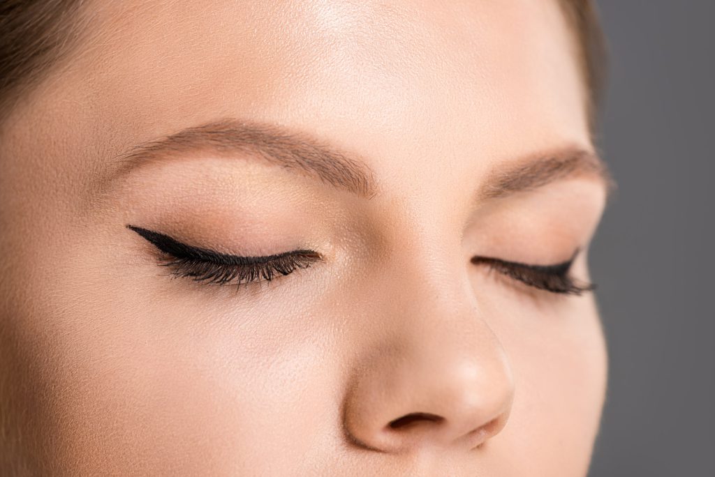 partial view of woman with black eyeliner on eyelids